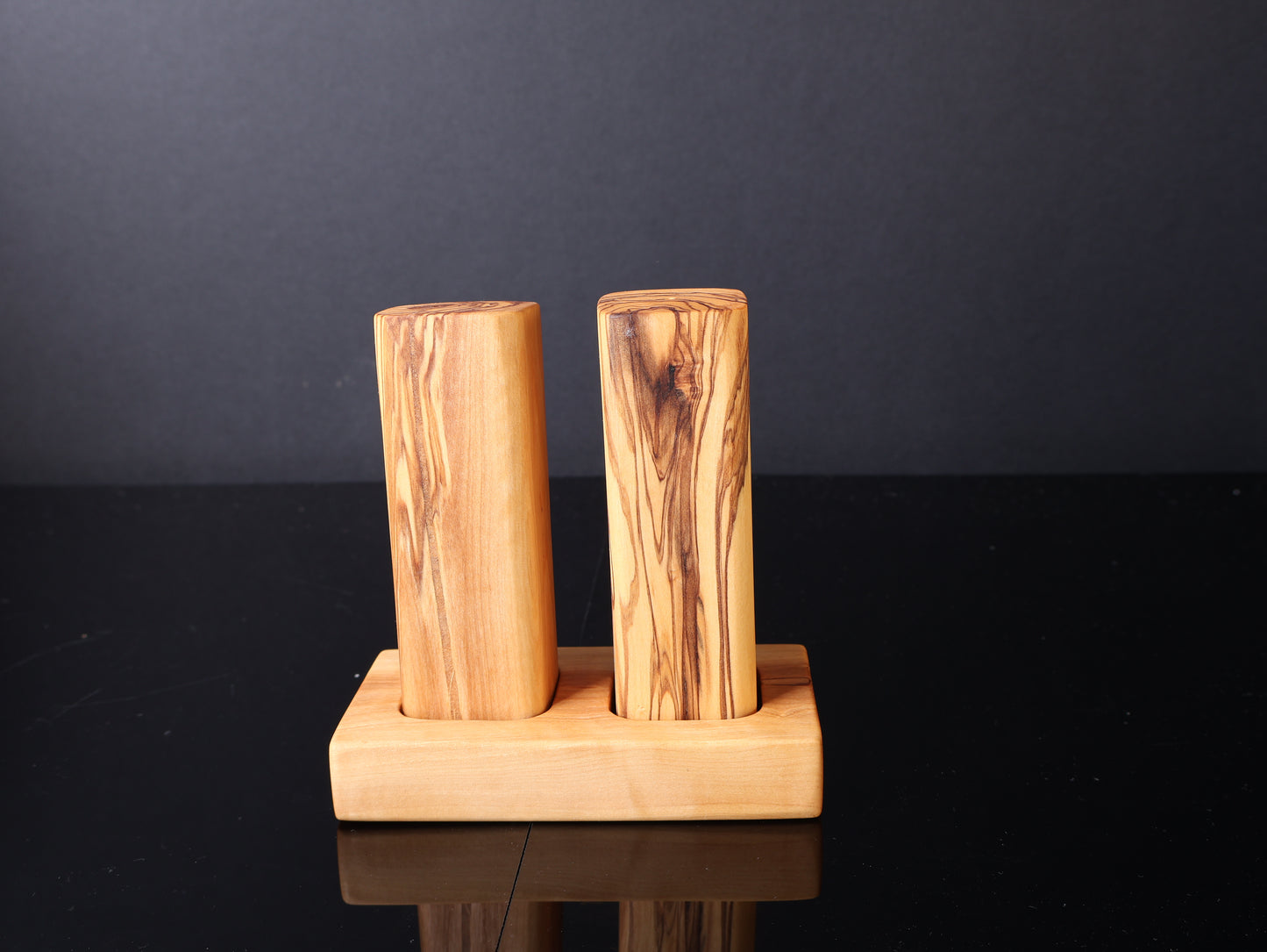 Two wooden cylindrical objects on a wooden stand against a dark background