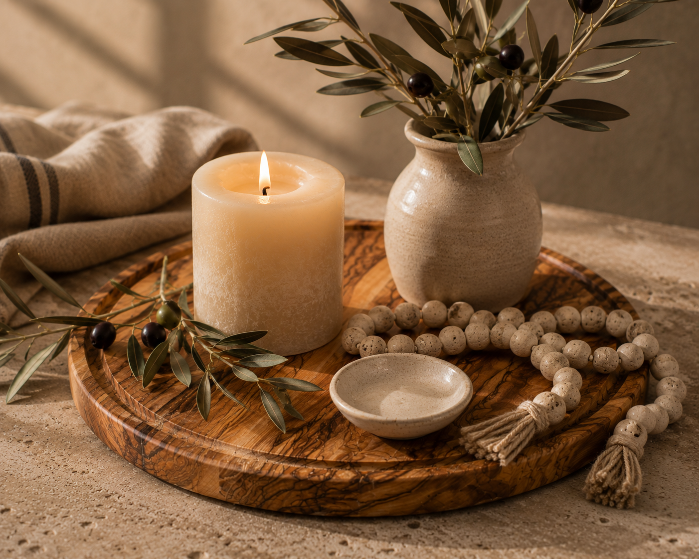 The Grove Collection 25 cm olive wood round tray styled as a home décor display with a pillar candle, ceramic vase and beads — Wild Olive Co.

