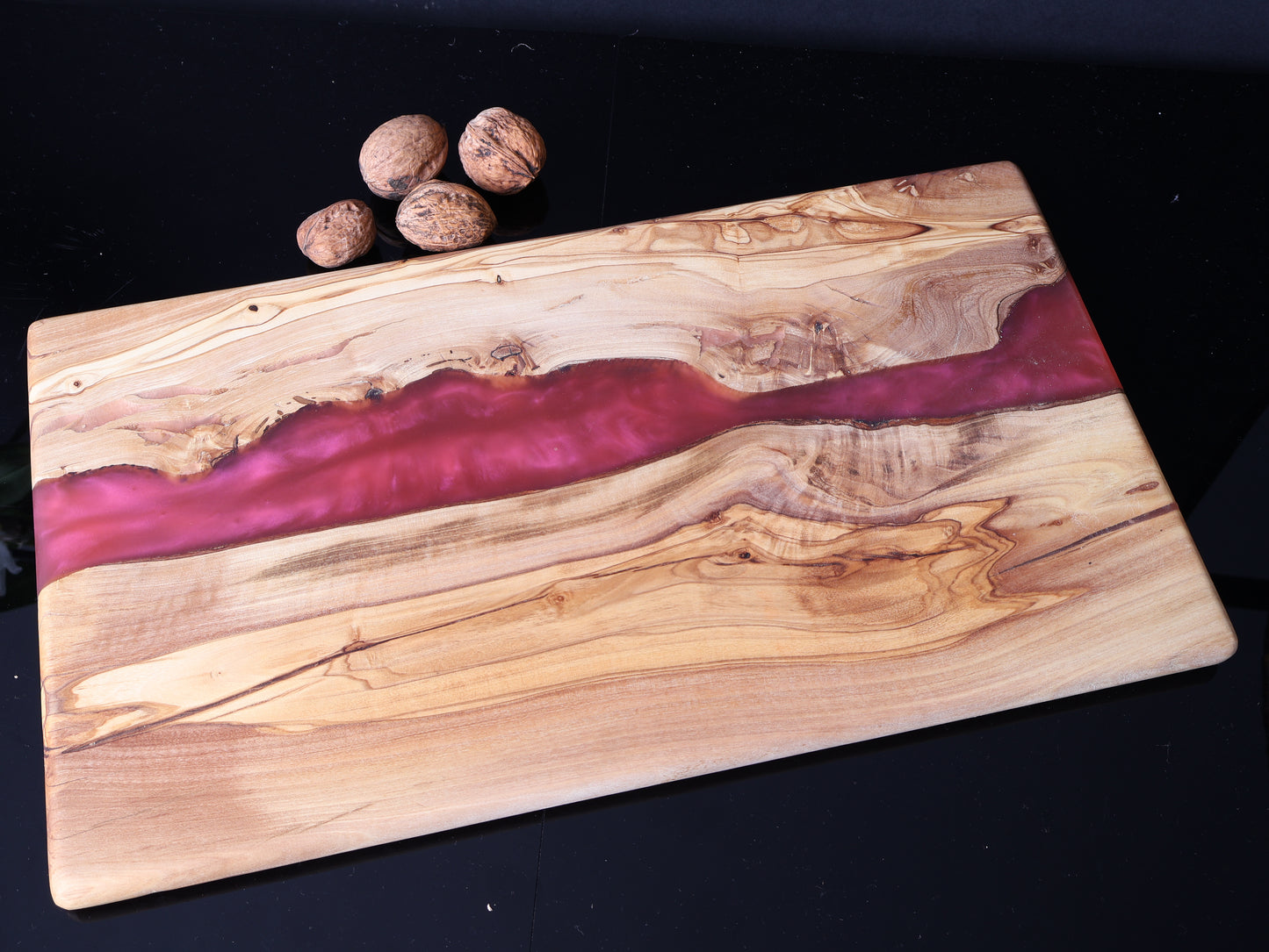 Wooden cutting board with purple resin inlay on a black background
