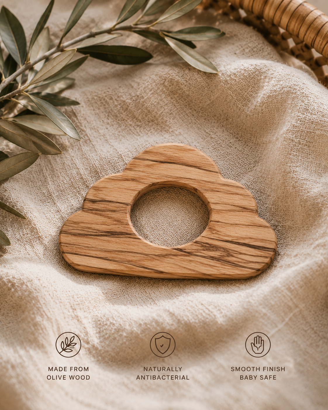 Wooden cloud-shaped object on a textured fabric background with olive leaves.