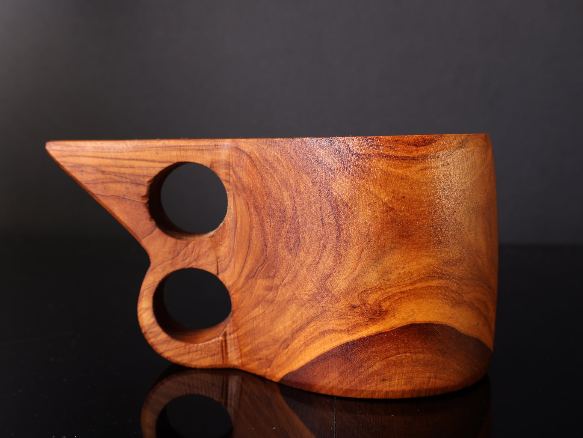 Wooden cutting board with two holes on a dark background