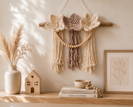 Decorative wall hanging with flowers, books, and a vase on a shelf.