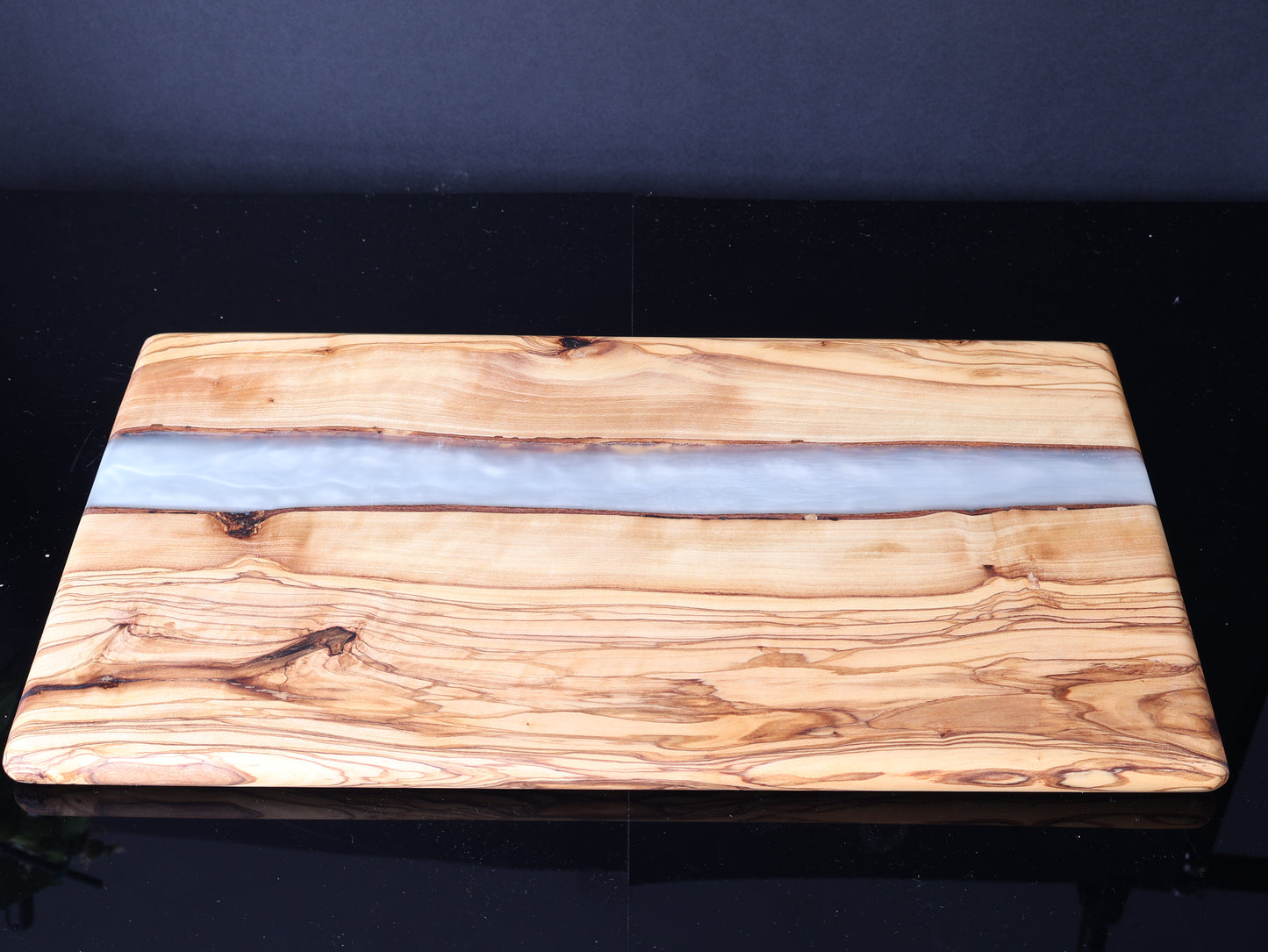 Wooden cutting board with a white resin stripe on a black background