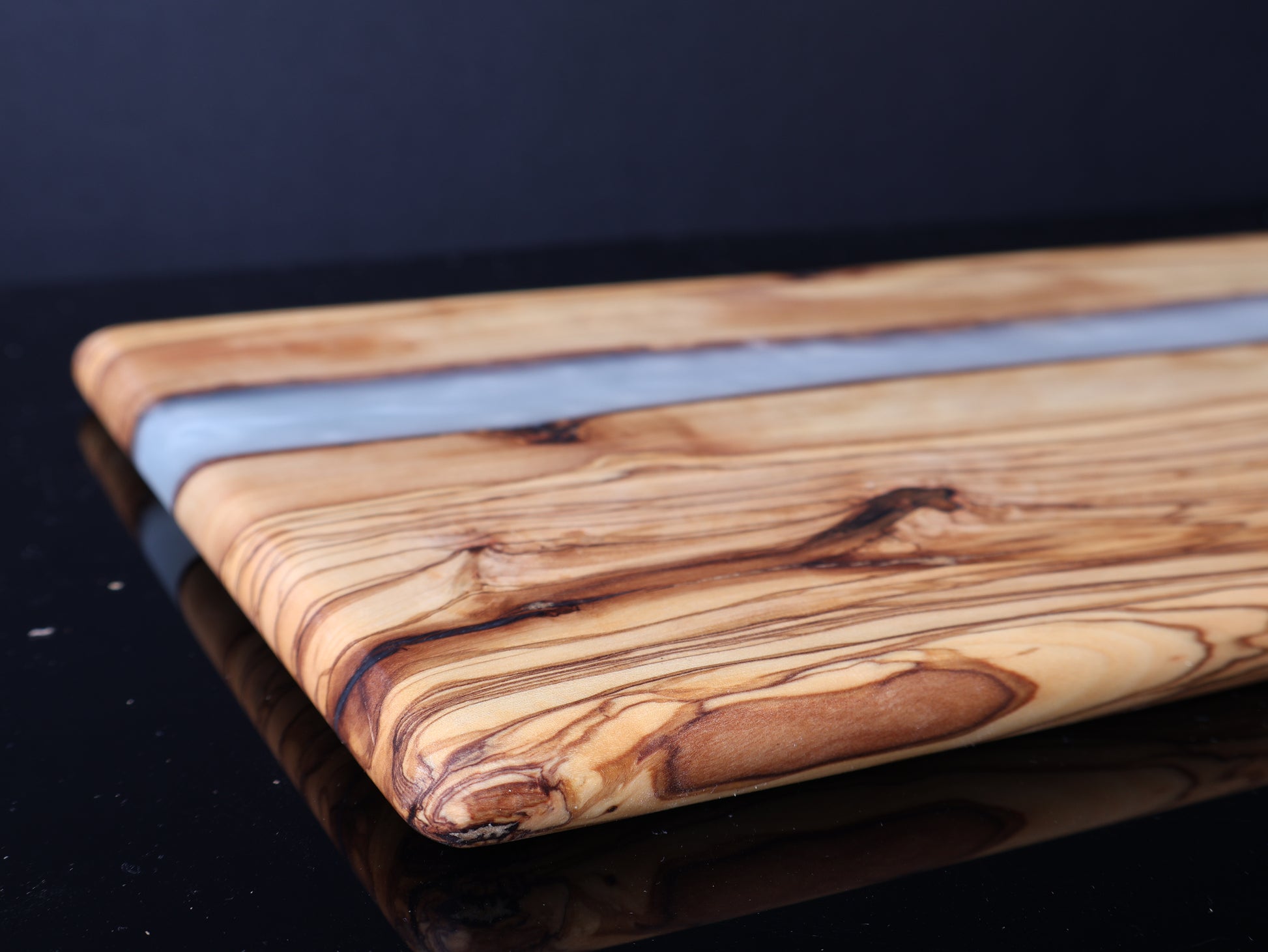 Wooden cutting board with a white resin inlay on a dark surface